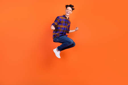 Full size photo of millennial hooray guy jump wear shirt jeans sneakers isolated on orange backgroundの写真素材