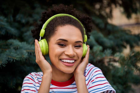 Photo of young cheerful black woman happy positive smile enjoy listen music headphones nature...