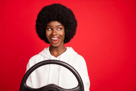 Photo of funky brunette hair young lady tongue out look empty space drive wear white hoodie isolated on red color backgroundの写真素材
