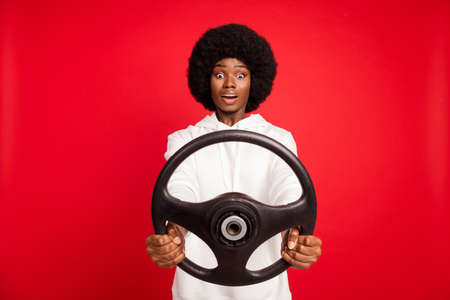 Photo of scary curly hairdo young lady drive car wear white sportswear isolated on red color backgroundの写真素材