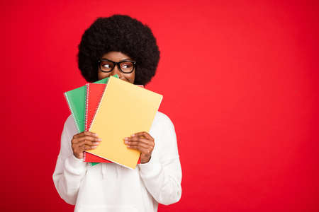 Photo of funny curly hairdo young lady cover face hold books look empty space wear bag eyewear white...