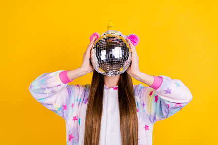 Portrait of attractive funny girl wearing kingurumi closing face shiny ball isolated over bright...