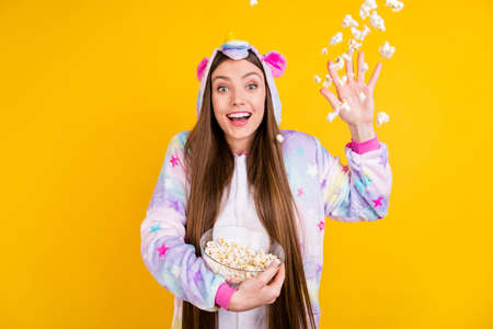 Photo of amazed shocked happy young woman fly throw pop corn childish isolated on yellow color...