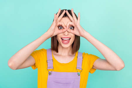 Photo of positive young happy cheerful woman make fingers glasses okay isolated on pastel teal color...
