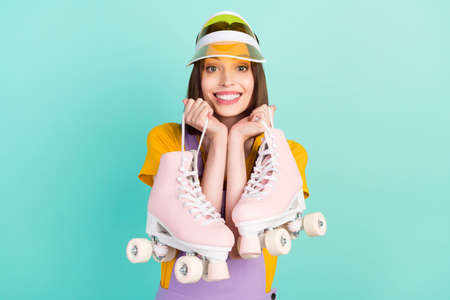Photo of cheerful young happy woman wear hat smile hold rollers sportive isolated on pastel teal...