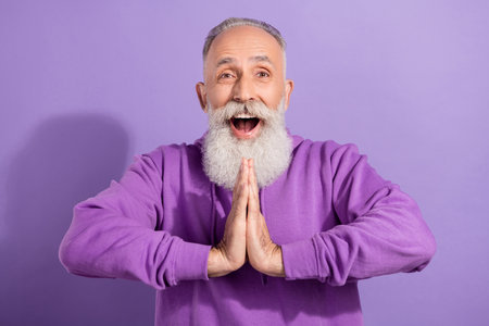 Portrait of attractive amazed cheerful grey-haired man asking favor request isolated over purple...