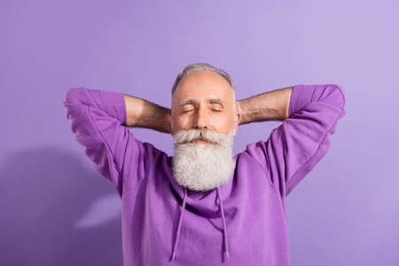 Portrait of attractive dreamy grey-haired man resting free time isolated over purple violet color backgroundの写真素材