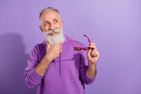 Portrait of attractive minded cheery grey-haired man touching beard thinking copy space isolated...