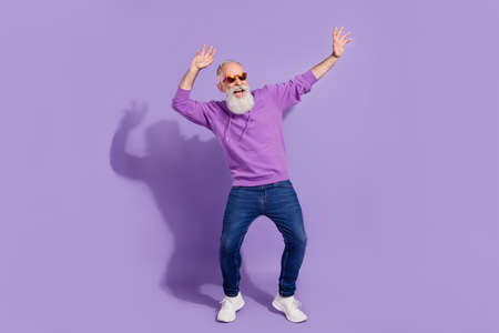 Full length body size view of attractive cheerful carefree grey-haired man dancing fooling isolated over purple violet color backgroundの写真素材