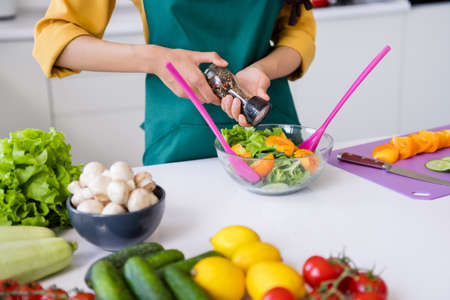 Photo of adorable pretty dark skin woman dressed yellow shirt cooking flavoring salad indoors house home roomの写真素材
