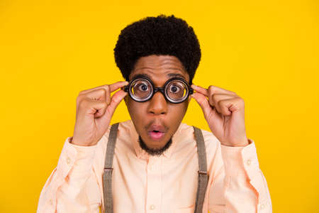Photo portrait man in shirt wearing spectacles checking eyesight amazed isolated bright yellow color backgroundの写真素材