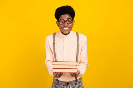 Photo portrait man in shirt wearing glasses keeping book pile isolated bright yellow color backgroundの写真素材