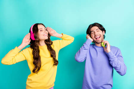 Photo of young excited couple happy positive smile enjoy melody wireless headphones isolated over teal color backgroundの写真素材
