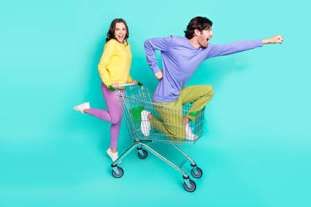 Full body photo of young couple happy positive smile guy ride cart power isolated over teal color...