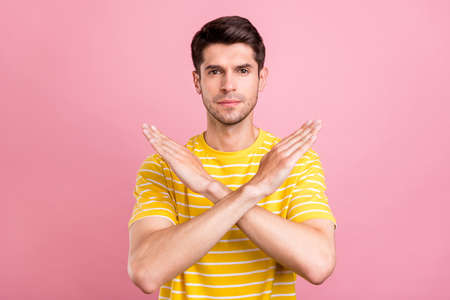 Photo of young serious calm man hold hands crossed prohibition stop sign isolated on pastel pink...