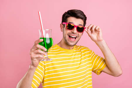 Photo of happy charming cheerful man hold cocktail cheers wear sunglass isolated on pink color backgroundの写真素材