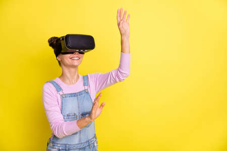 Photo of sweet charming young lady dressed jeans overall plying game vr glasses empty space isolated...