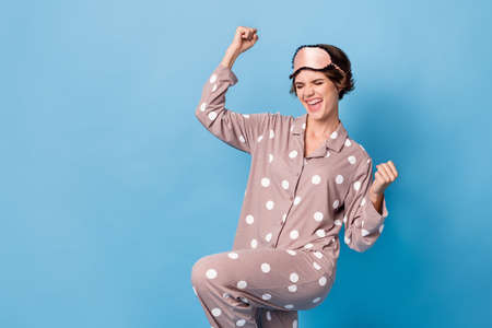 Photo of victorious young happy woman raise fists wear pajama isolated on pastel blue color...