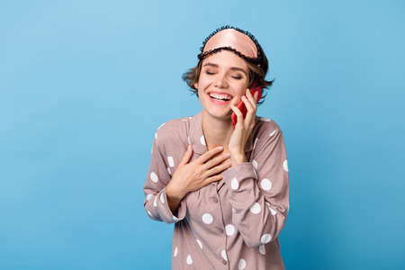 Photo of young girl happy positive smile talk cellphone hand on chest grateful isolated over blue color backgroundの写真素材