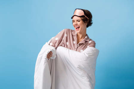 Photo of young cheerful girl happy positive smile excited cover duvet isolated over blue color...