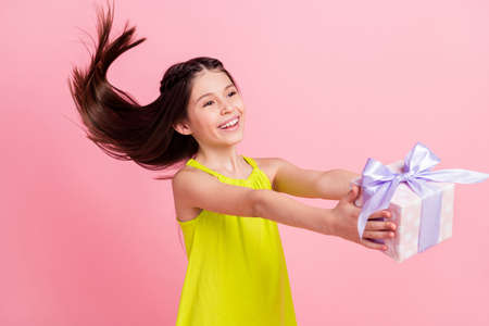 Photo of adorable sweet small schoolgirl dressed yellow outfit holding present looking empty space isolated pink color backgroundの写真素材