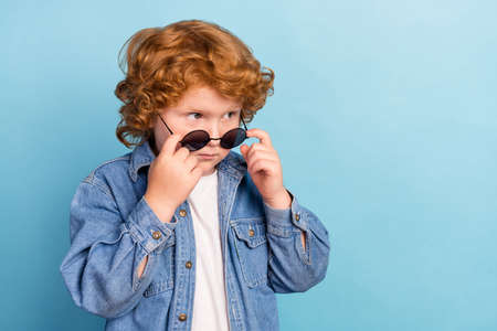 Photo portrait curly little boy looking empty space wearing stylish sunglass isolated pastel blue color backgroundの写真素材