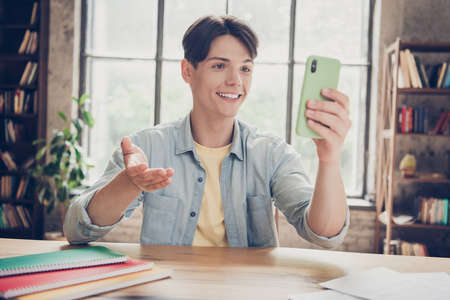 Portrait of attractive cheerful guy making video call preparing homework having fun at loft industrial interior indoorsの写真素材