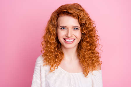 Photo portrait of red haired curly woman smiling in white sweater isolated on pastel pink color...