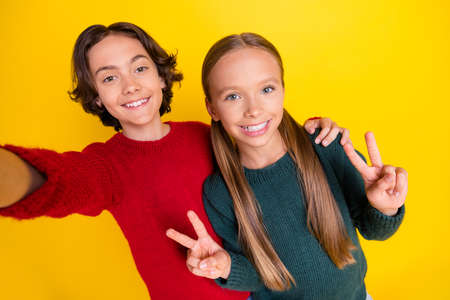 Photo portrait two children taking selfie showing peace isolated bright yellow color backgroundの写真素材