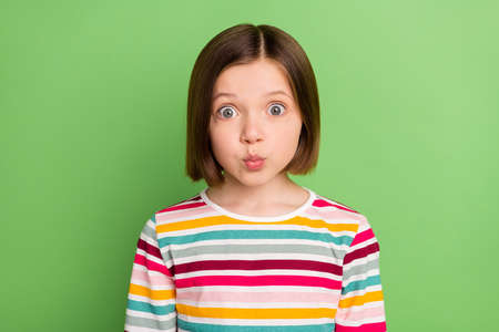 Photo of young little girl happy positive smile pouted lips amazed surprised isolated over green color backgroundの写真素材
