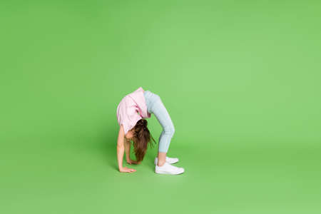 Full size profile side photo of young little girl stand bridge pose gymnastics sporty isolated over green color backgroundの写真素材