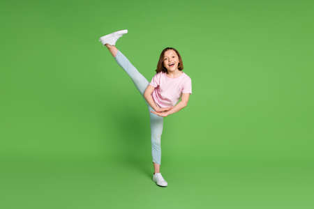 Full size photo of young little girl leg acrobatics aerobics sportive isolated over green color backgroundの写真素材