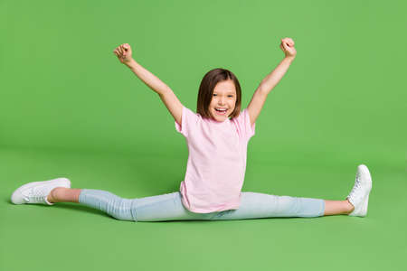 Full body photo of young girl sit floor split stretch happy positive smile rejoice success isolated over green color backgroundの写真素材