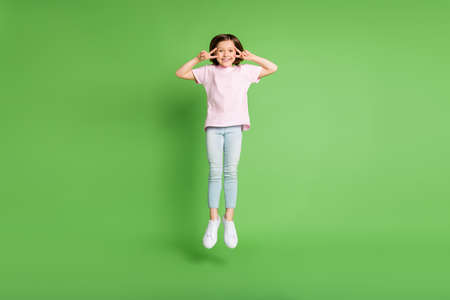 Full body photo of young girl happy positive smile jump up show peace cool v-sign isolated over...