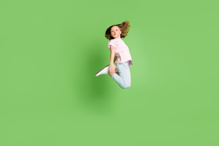 Full body profile side photo of young girl happy positive smile jump pouted lips isolated over green color backgroundの写真素材