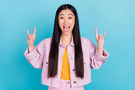 Portrait of attractive cheerful girl showing double horn sign having fun isolated over bright blue color backgroundの写真素材