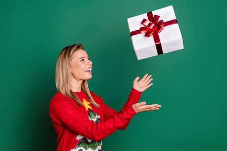 Portrait of attractive trendy cheerful girl throwing giftbox having fun isolated over green color...