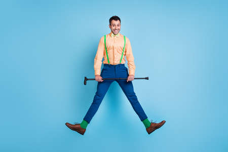 Photo of cheerful guy jump hold walking cane wear suspenders shirt bow tie isolated blue color...