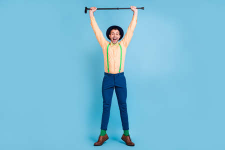 Full size photo of hooray brunet man stand with cane wear cap shirt trousers socks shoes isolated on blue color backgroundの写真素材