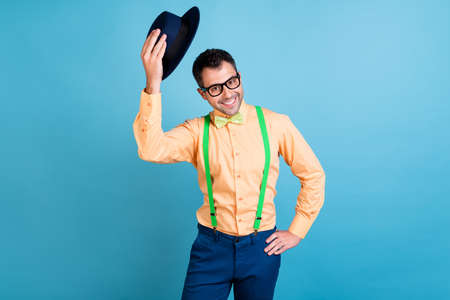 Photo of friendly brunet man hold cap wear eyewear peach shirt spectacles isolated on blue color backgroundの写真素材