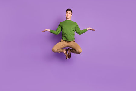 Full body photo of young funny brunet guy jump wear sweater trousers sneakers isolated on purple...