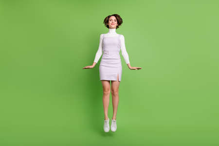 Full length body size photo girl jumping up smiling happy isolated pastel green color backgroundの写真素材