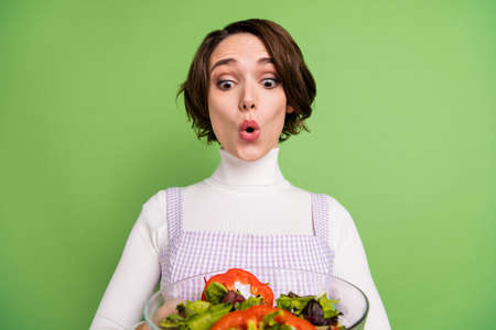 Photo of young girl amazed shocked look salad dieting weight loss vegetarian isolated over green...