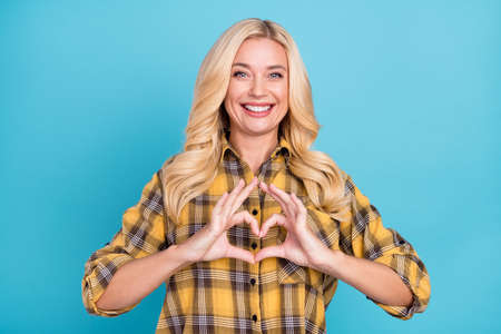 Portrait of attractive cheerful wavy-haired woman showing heart feelings isolated over bright blue color backgroundの写真素材