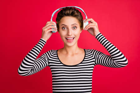 Photo portrait woman with bob hair amazed listening music in headphones isolated bright red color...