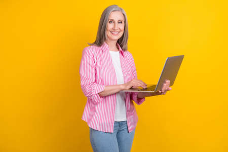 Photo of aged business woman happy positive smile work programmer computer isolated over yellow color backgroundの写真素材