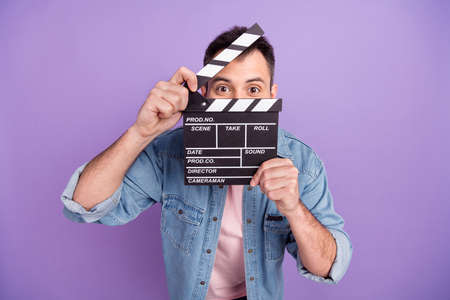 Photo of young guy close cover face clapboard look scene cut make movie producer isolated over purple color backgroundの写真素材