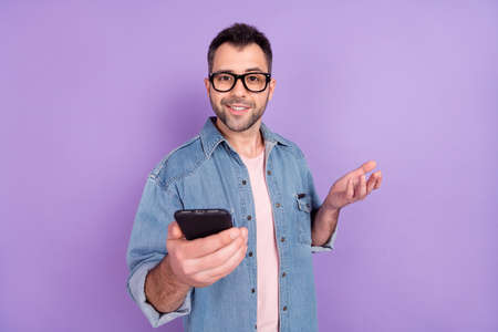 Photo portrait male journalist keeping cellphone wearing glasses taking interview isolated pastel violet color backgroundの写真素材