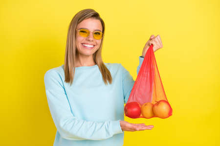 Portrait of attractive cheerful girl holding bag apples organic diet supermarket isolated over...