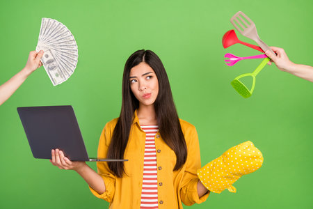 Photo of think brunette hairdo young lady look empty space hold laptop wear yellow shirt isolated on pastel green color backgroundの写真素材